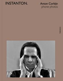 Snapshot of Australian singer songwriter Nick Cave, with eyes closed and fingers at temples, INSTANTON, in black font above, on brown cover.