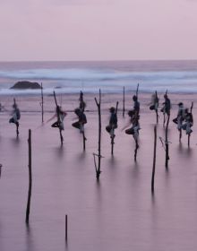 Group of Asian sea fishermen on stilts, serene lilac seascape behind, CATCH ASIA UNIQUE in white font above and below.