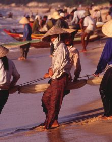 Group of Asian sea fishermen on stilts, serene lilac seascape behind, CATCH ASIA UNIQUE in white font above and below.