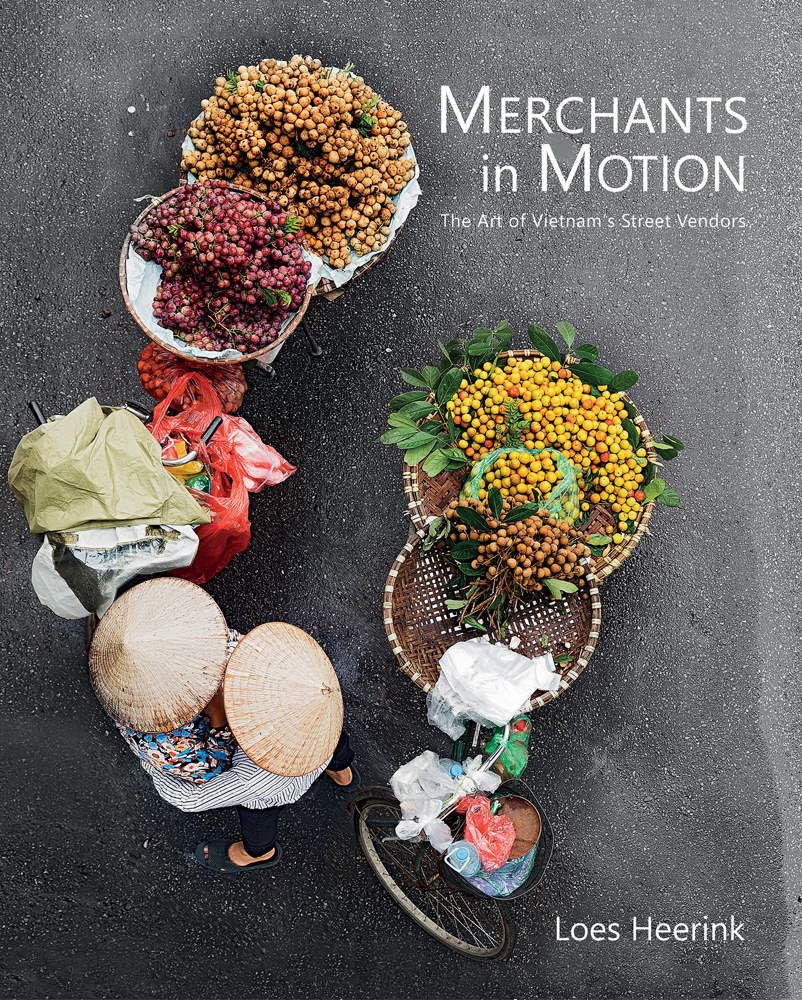 Book cover of Merchants in Motion, The Art of Vietnam's Street Vendors, featuring an aerial view of two Vietnamese street vendors in leaf hats, next to bikes with trailers of colourful fruits. Published by Waanders Publishers.