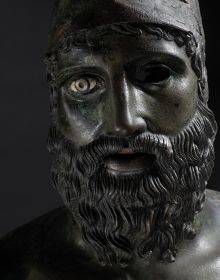 Greek bronze sculpture of naked bearded Riace warrior, The Riace Bronzes, in pale green font below,