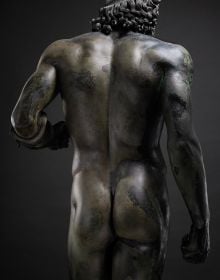 Greek bronze sculpture of naked bearded Riace warrior, The Riace Bronzes, in pale green font below,